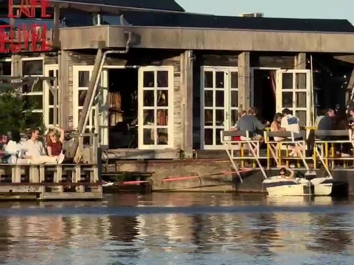 The sunlit terrace and dock of Café de Ceuvel seen from the water
